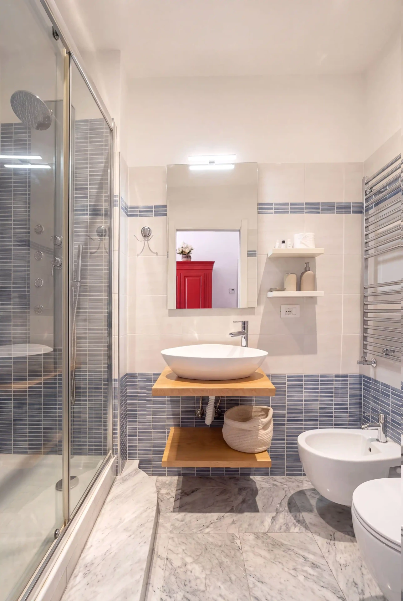 Bagno privato di Borgogna: doccia in vetro, lavabo d’appoggio su mensola in legno, pavimento in marmo e decoro blu