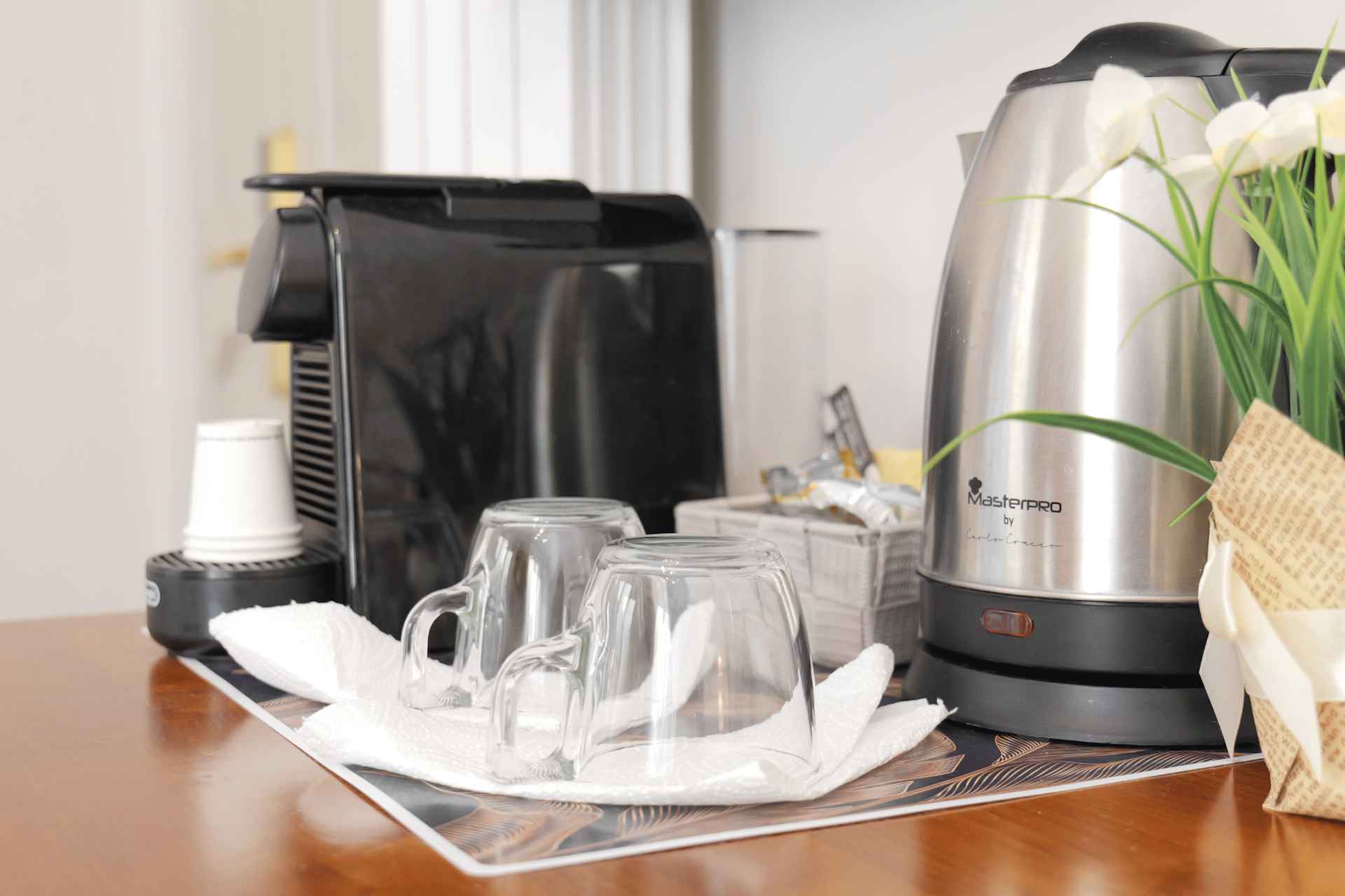 Angolo tè e caffè con macchina a capsule, bollitore e bicchieri in vetro