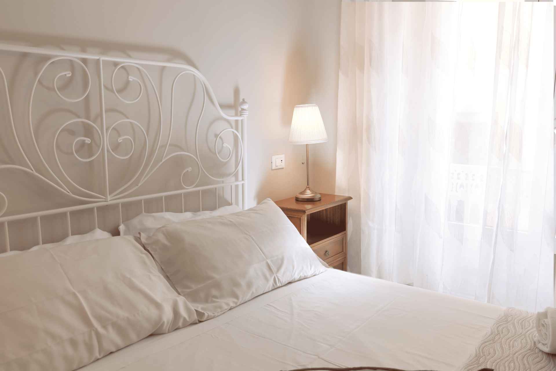 Il letto di Cachemire con le tende chiare che filtrano la luce della finestra