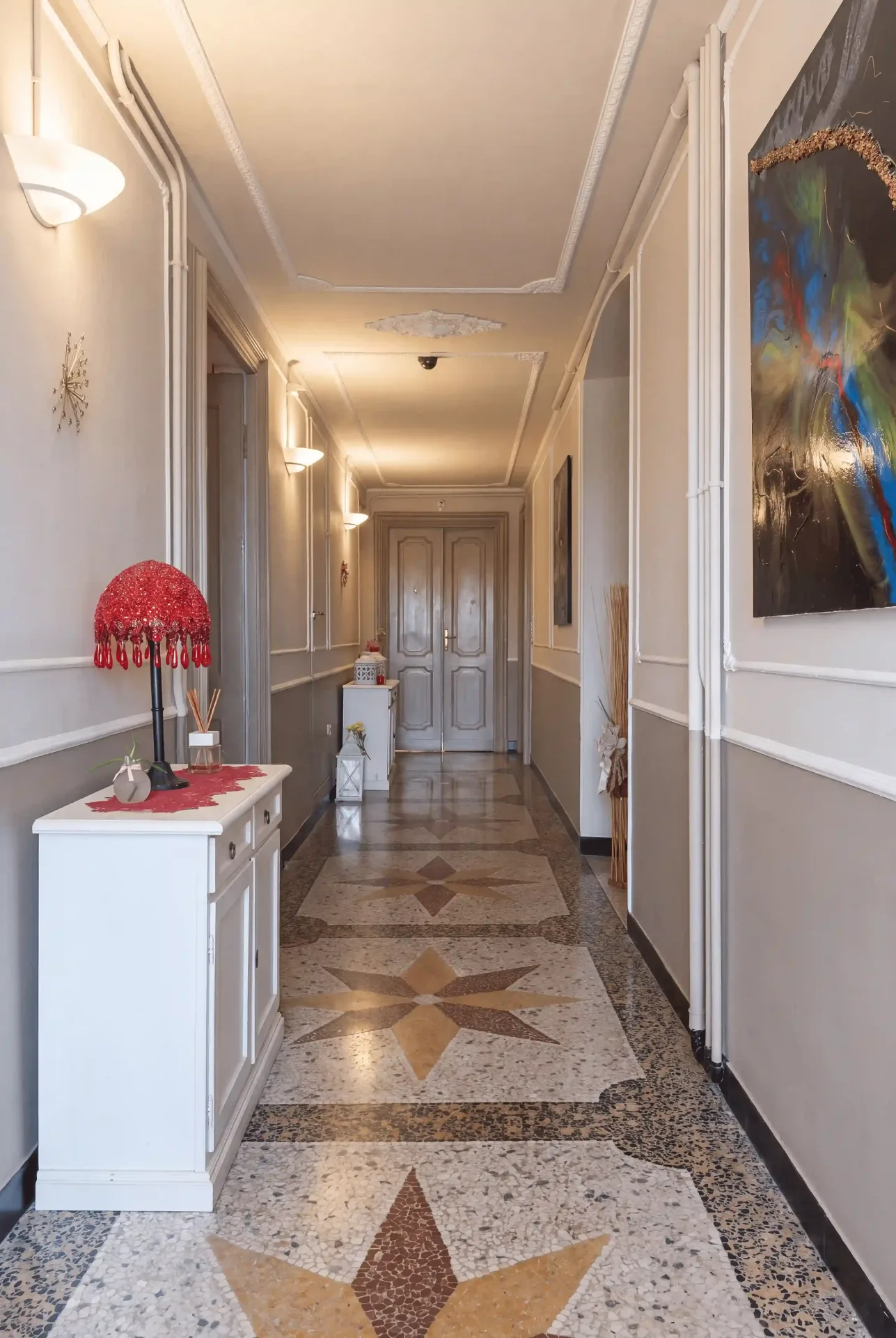 Corridoio luminoso della casa, quadri alle pareti e pavimento in graniglia con decorazioni geometriche