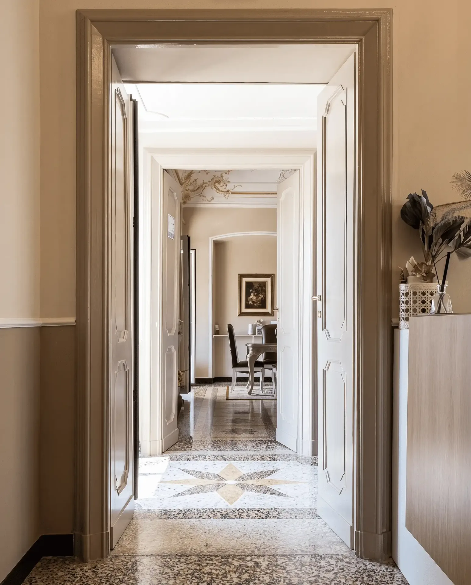 Porte laccate aperte verso il salotto e pavimento in graniglia genovese con motivo geometrico a stella