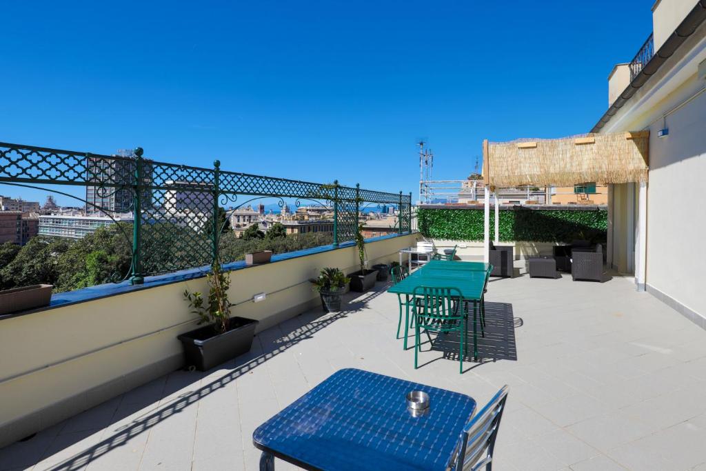 Terrazzo comune con tavoli verdi e blu, ringhiera decorata e vista sulla città e sul mare
