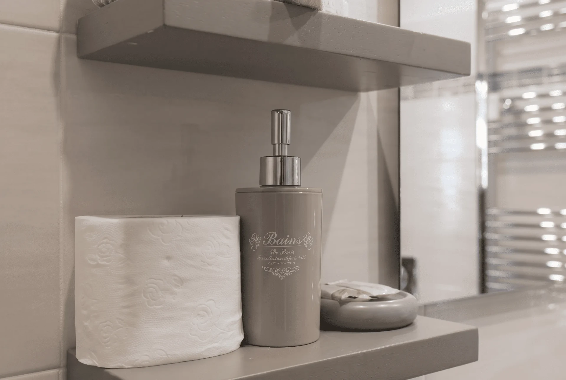 Mensola grigia in bagno con carta igienica e dispenser di sapone