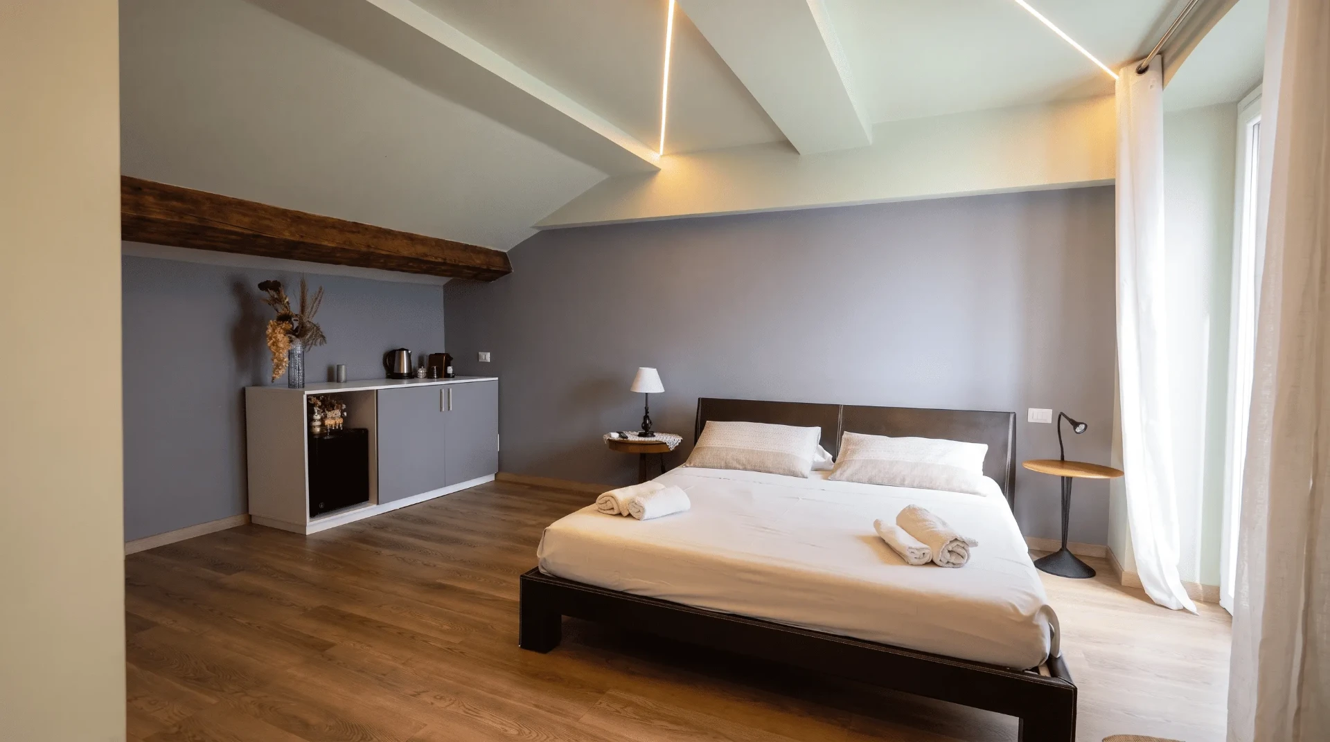 Vista ampia della Suite con letto, comodini, trave in legno a vista e angolo caffè