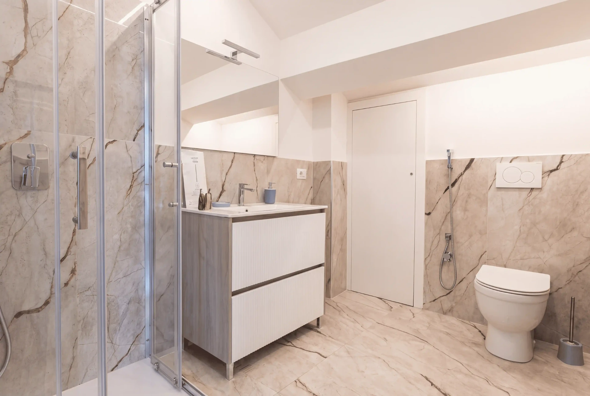 Bagno privato della Suite con rivestimento in marmo venato, doccia in vetro, mobile lavabo e WC